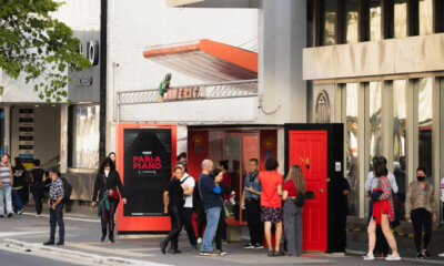 Pessoas interagindo com a porta vermelha do Parla Piano na Avenida Paulista.