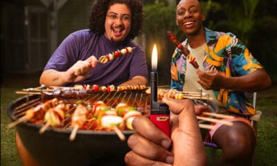 Pessoa acendendo uma vela de aniversário com um isqueiro BIC, rodeada por amigos sorrindo em uma comemoração intimista, simbolizando conexão emocional e momentos especiais da vida cotidiana.