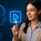 Representação digital de uma cabeça humana em estilo wireframe azul observando um ícone de play holográfico, simbolizando inteligência artificial e publicidade em vídeo.