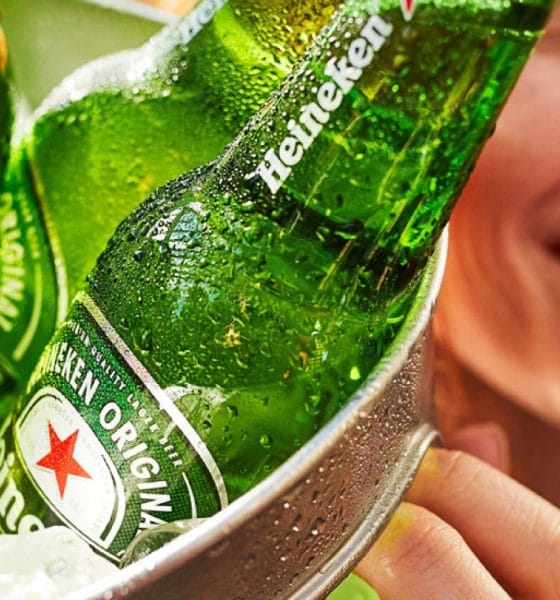 Fotografia conceitual de rótulos e embalagens inspiradas na paleta verde Heineken, com destaque para uma estrela vermelha estilizada ao lado do wordmark, representando a evolução do logo ao longo do tempo.